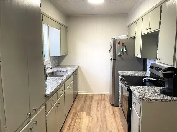 a kitchen with granite countertop a sink stove and refrigerator