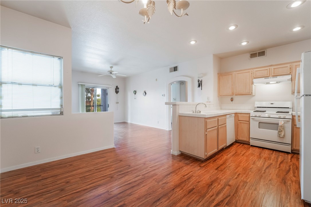 2201 Ramsgate Drive, Unit 823 Henderson, NV 89074 - Photo 3 of 31 Kitchen with visible vents, light brown cabinetry, under cabinet range hood, white appliances, and a peninsula