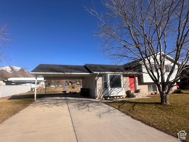 1045 South 850 East Springville, UT 84663 - Photo 1 of 1 Tri-level home featuring an attached carport, brick siding, fence, driveway, and a front yard