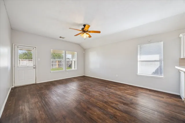 a view of an empty room with a window and wooden floor