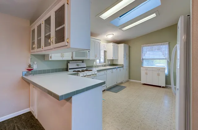 a kitchen with granite countertop white cabinets white stainless steel appliances with a sink and dishwasher