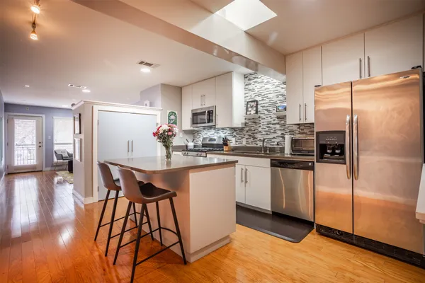 a kitchen with stainless steel appliances a refrigerator a sink dishwasher with a dining table and chairs