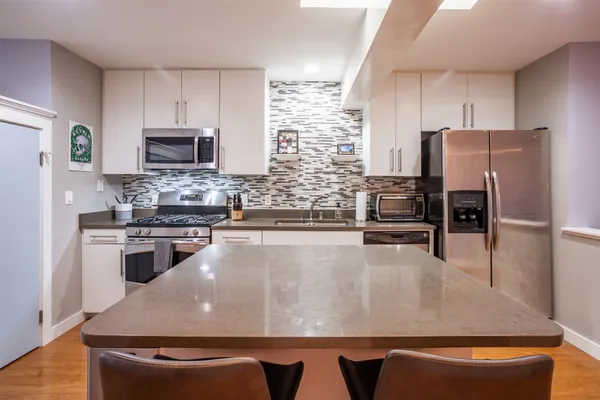 a view of a kitchen with kitchen island a counter top space stainless steel appliances and cabinets