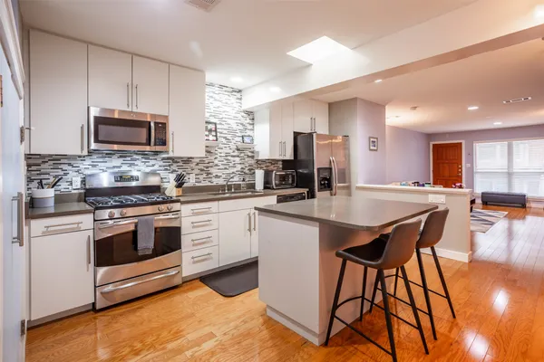 a kitchen with stainless steel appliances kitchen island granite countertop a stove a sink a microwave and a refrigerator