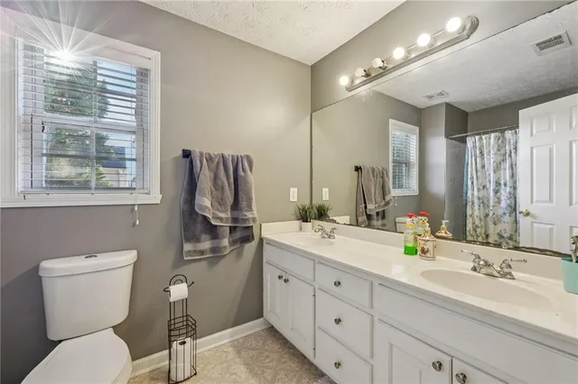 a bathroom with a granite countertop toilet sink and mirror