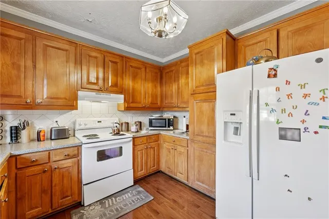 a kitchen with stainless steel appliances granite countertop a refrigerator a sink dishwasher and white cabinets with wooden floor