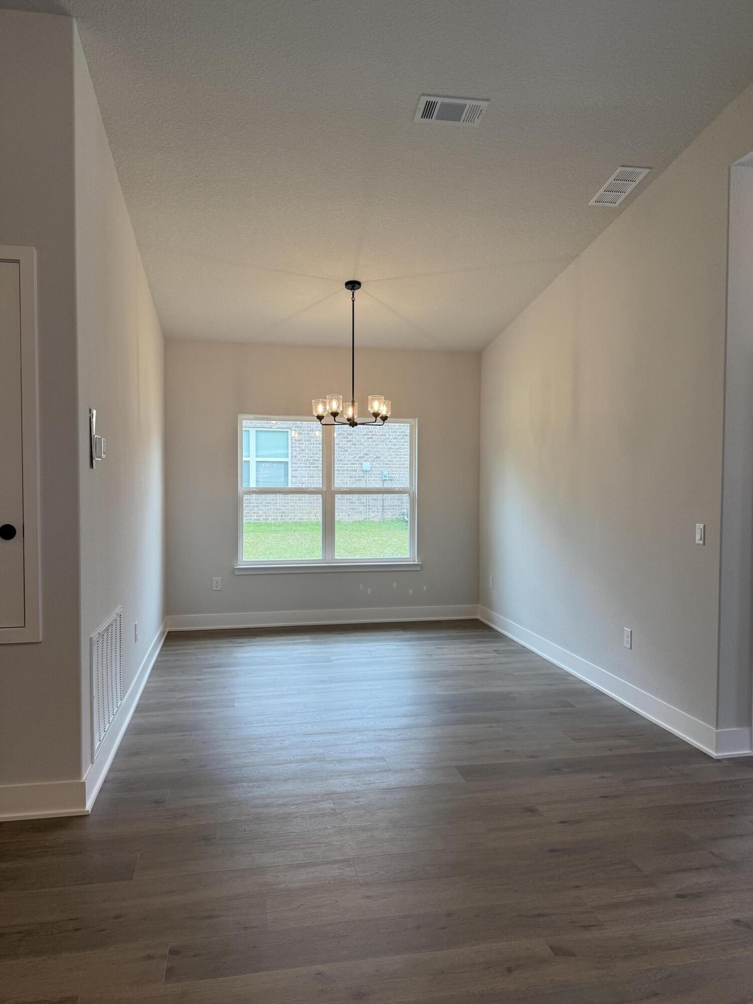 2411 Aleia Lane Crestview, FL 32536 - Photo 12 of 28 a view of a room with wooden floor chandelier and windows