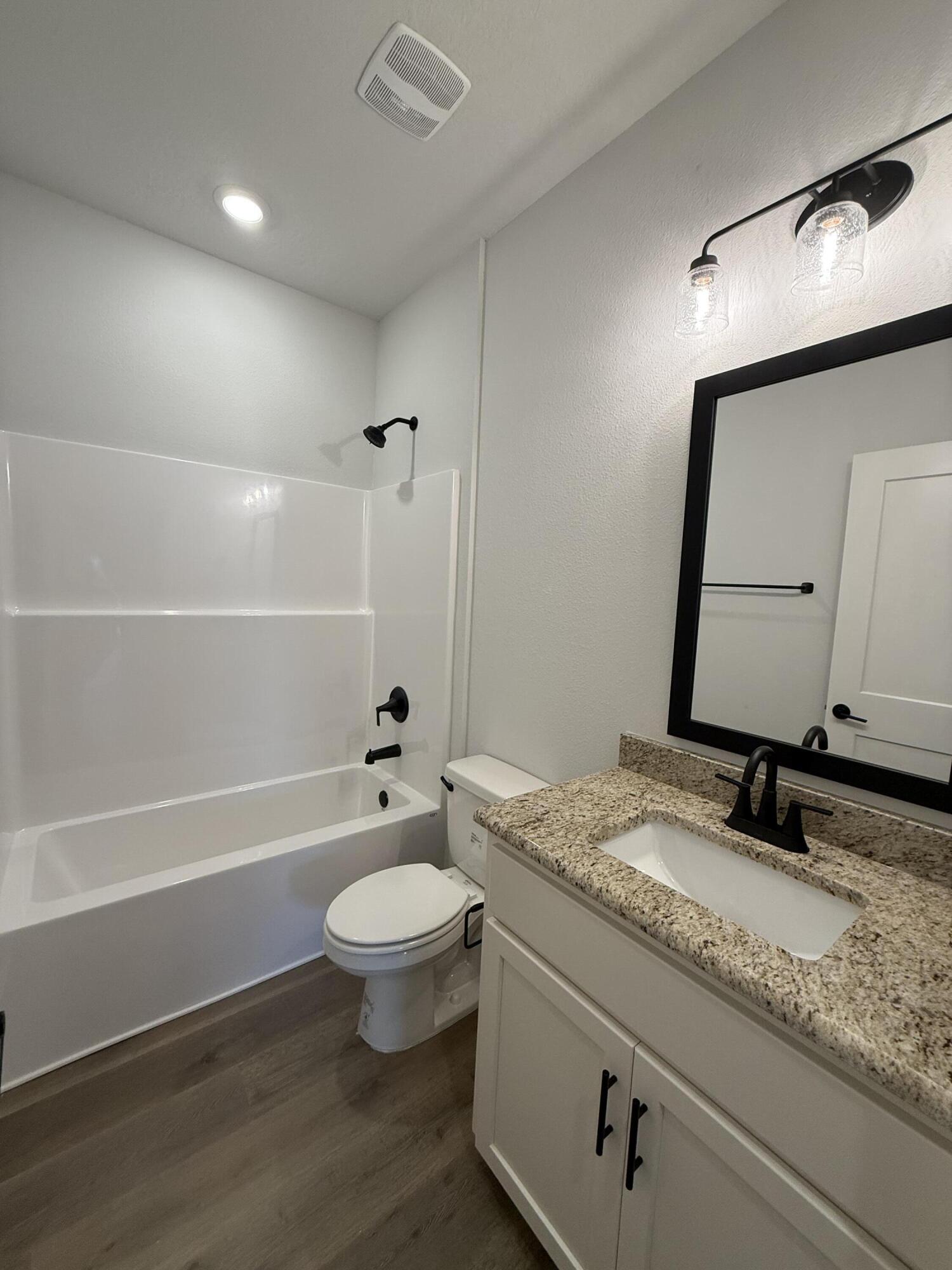 2411 Aleia Lane Crestview, FL 32536 - Photo 22 of 28 a bathroom with a granite countertop sink a toilet a mirror and bathtub