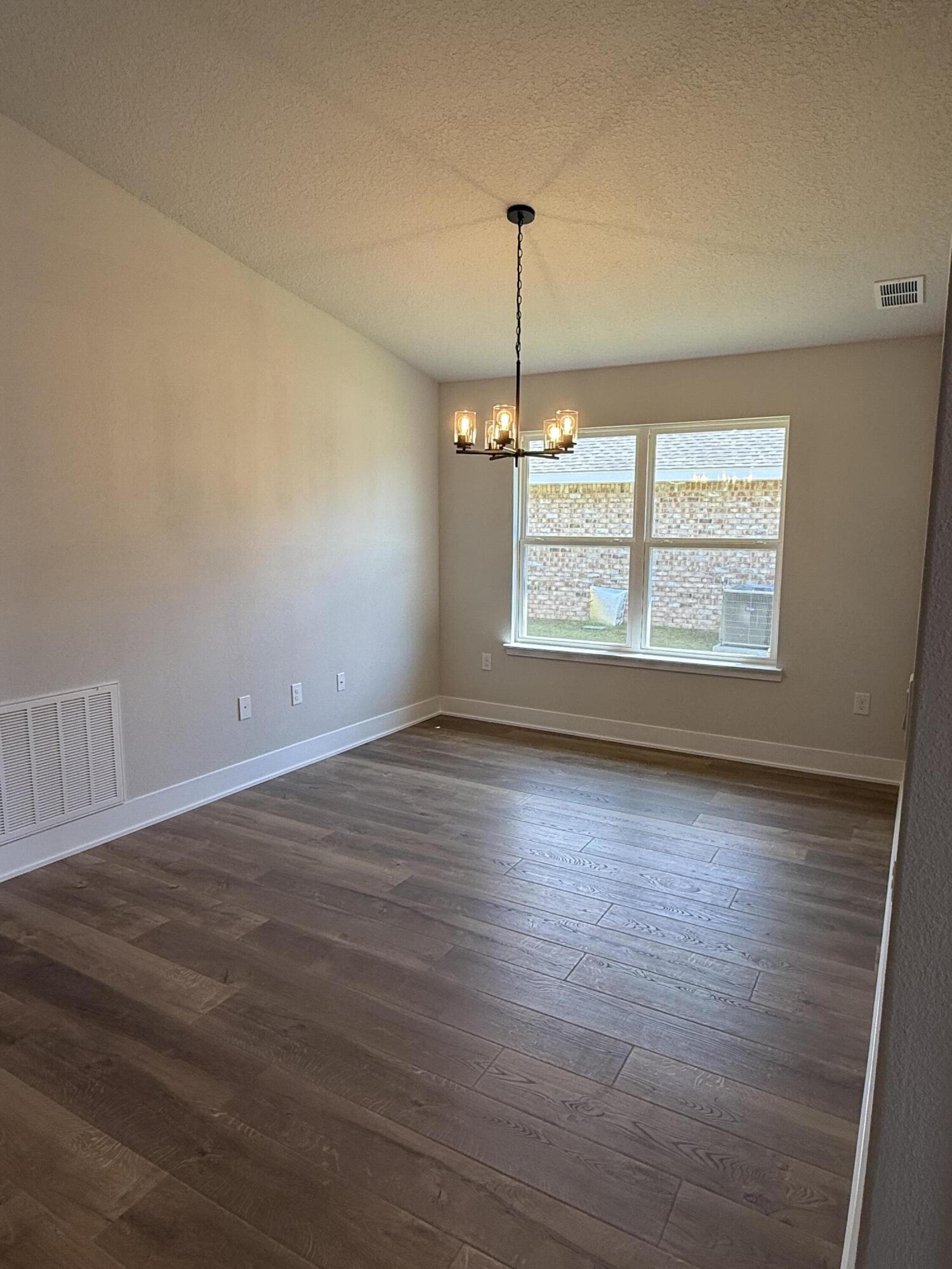 2411 Aleia Lane Crestview, FL 32536 - Photo 6 of 21 an empty room with wooden floor windows and glass door