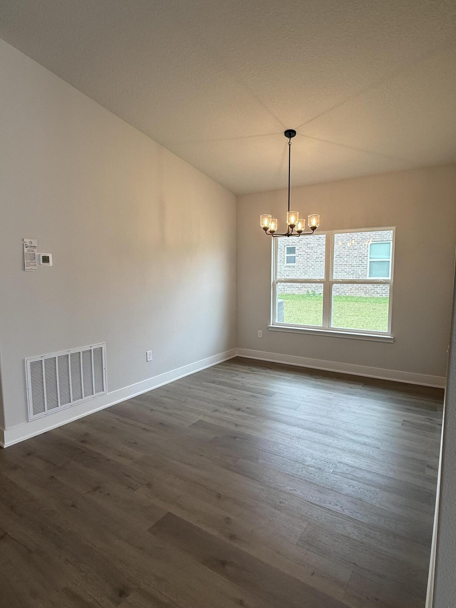 2411 Aleia Lane Crestview, FL 32536 - Photo 6 of 28 an empty room with wooden floor chandelier and windows