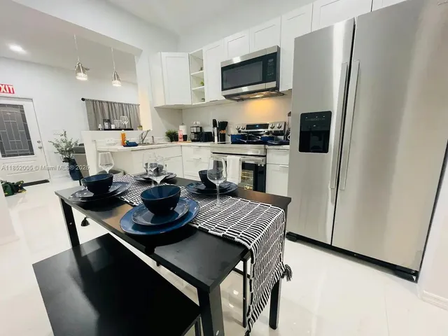 a kitchen with a refrigerator a stove a microwave a sink and white cabinets