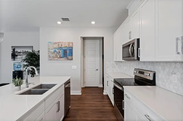 a kitchen with stainless steel appliances granite countertop a sink stove microwave and refrigerator