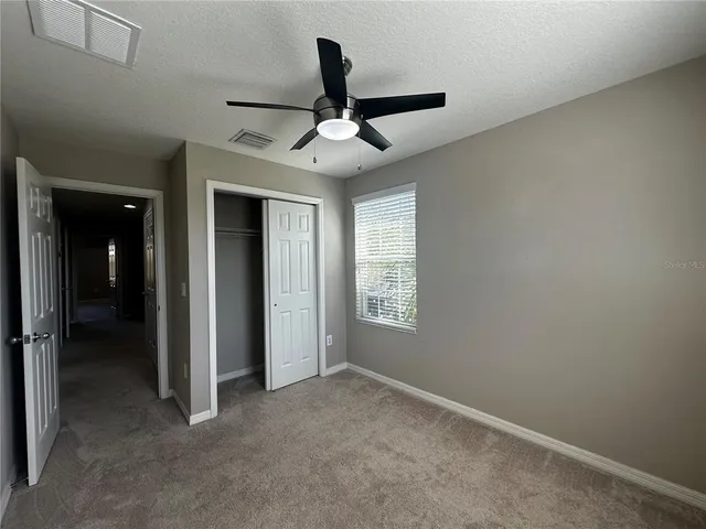 an empty room with windows and fan