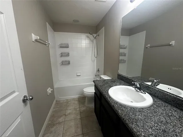 a bathroom with a granite countertop sink a toilet and shower