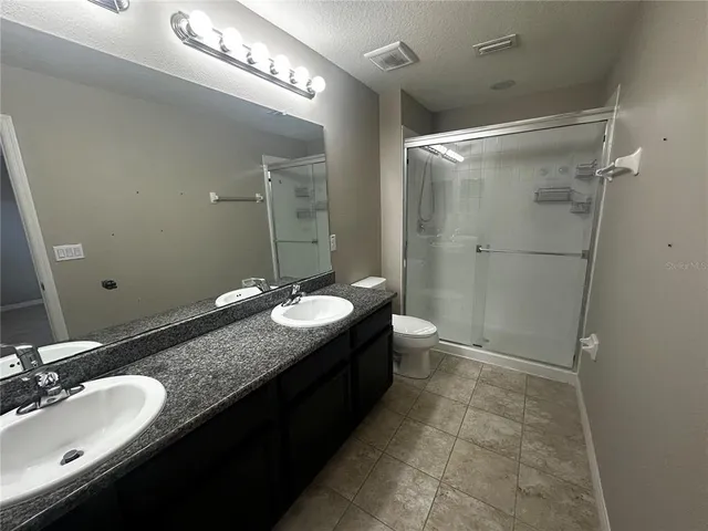 a bathroom with a granite countertop sink toilet a mirror and shower