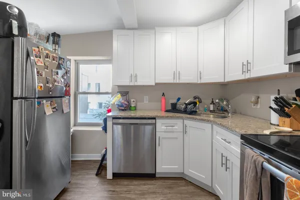 a kitchen with stainless steel appliances granite countertop a refrigerator sink and white cabinets