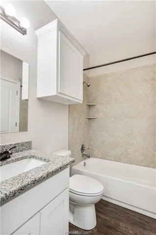 a bathroom with a granite countertop bathtub sink vanity mirror and toilet