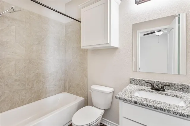 a bathroom with a granite countertop sink toilet and shower
