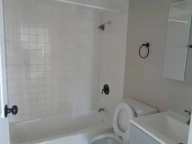 a bathroom with a granite countertop toilet a sink and shower