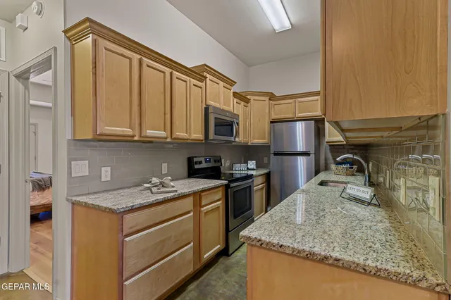 a kitchen with granite countertop stainless steel appliances a refrigerator a stove a sink and cabinets