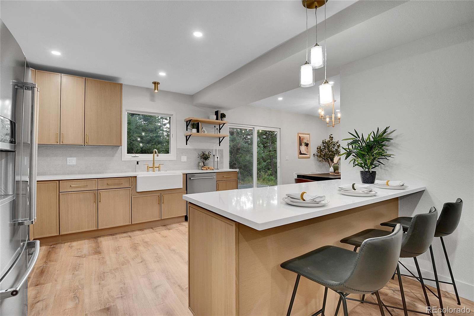 8919 South Hillview Road Morrison, CO 80465 - Photo 12 of 50 a kitchen with granite countertop a sink white cabinets a stove a dining table and chairs