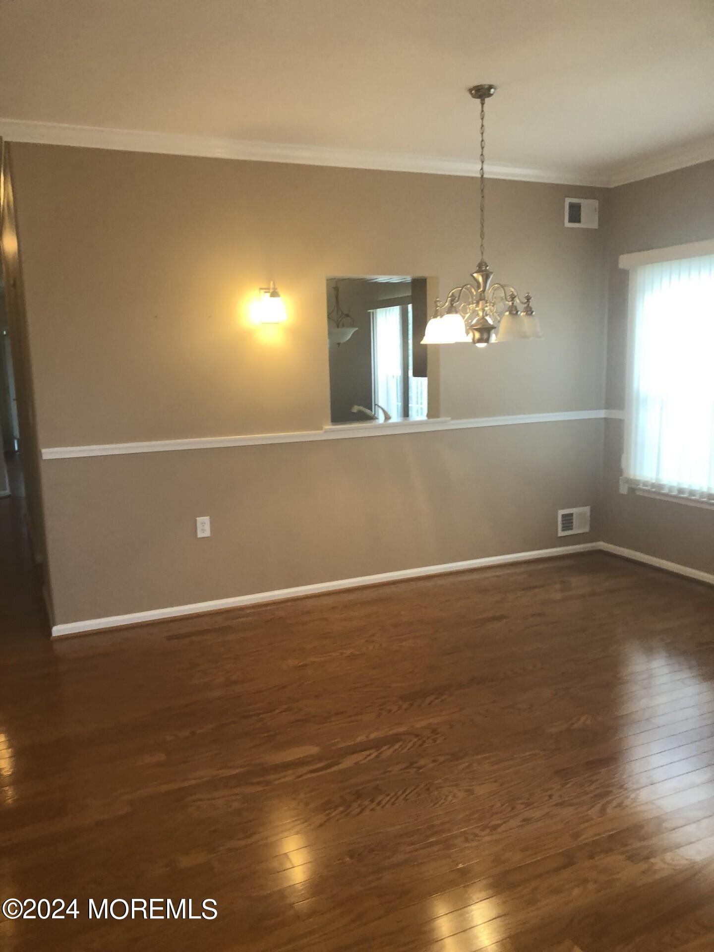 9 Modena Court Manchester Township, NJ 08759 - Photo 4 of 10 a view of an empty room with window and wooden floor