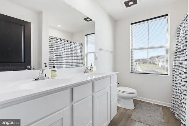 a bathroom with 2 sink toilet and a mirror