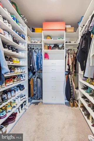 a view of walk in closet with clothes and shoes