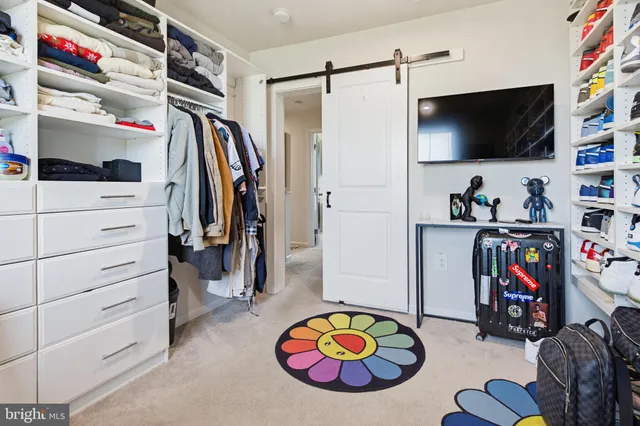 a view of walk in closet with clothes shoes and a couch