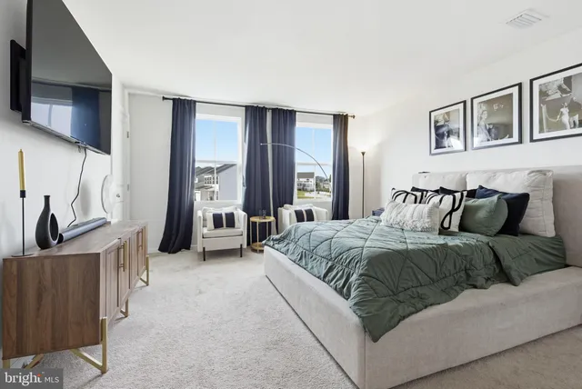 a spacious bedroom with a bed and a flat tv screen on dresser