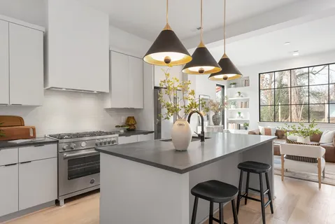 a kitchen with stainless steel appliances granite countertop a stove a sink a dining table and chairs with wooden floor