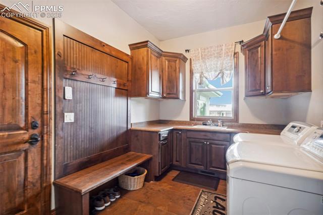 13665 Random Ridge View Colorado Springs, CO 80921 - Photo 17 of 49 Washroom with sink, washer and clothes dryer, dark tile patterned flooring, and cabinets