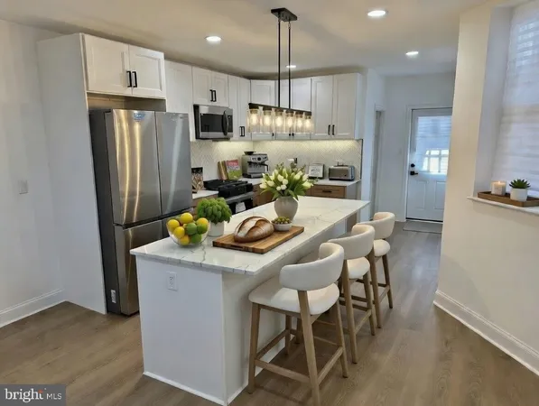 a kitchen with stainless steel appliances kitchen island granite countertop a refrigerator a stove a sink a dining table and chairs with wooden floor