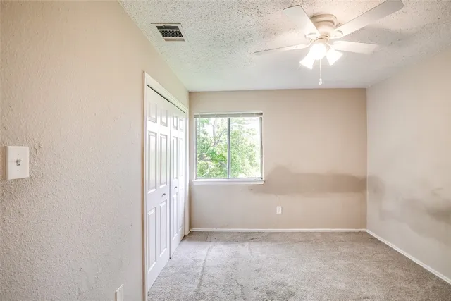 an empty room with windows and fan