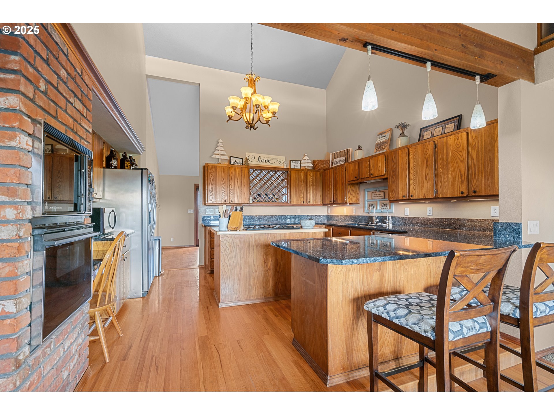 33551 East Progress Road Hermiston, OR 97838 - Photo 19 of 35 a open kitchen with stainless steel appliances granite countertop a refrigerator a sink dishwasher a stove and a dining table with wooden floor