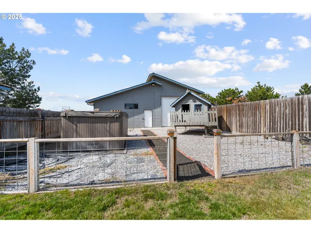 a view of a house with wooden fence next to a yard