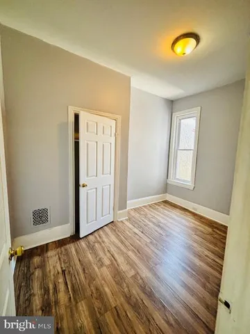 a view of empty room with window and wooden floor