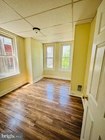 a view of an empty room with a window and wooden floor