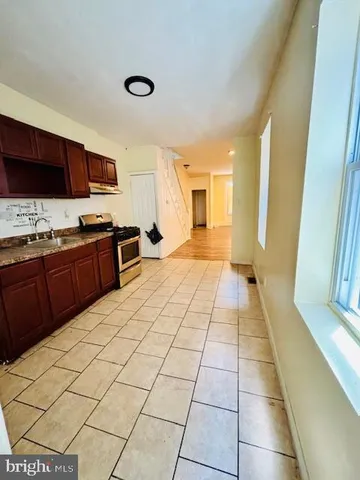 a large kitchen with stainless steel appliances a sink a stove a microwave a counter top space and cabinets