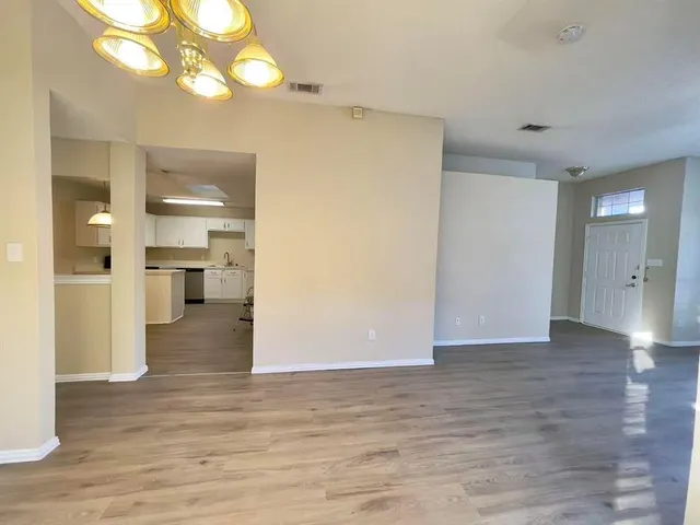 a view of a big room with wooden floor a kitchen space with a refrigerator