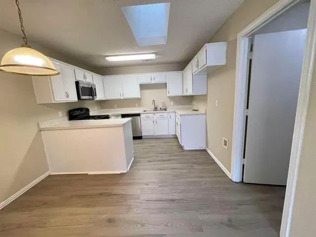 a kitchen with a refrigerator a stove top oven a sink and dishwasher with wooden floor