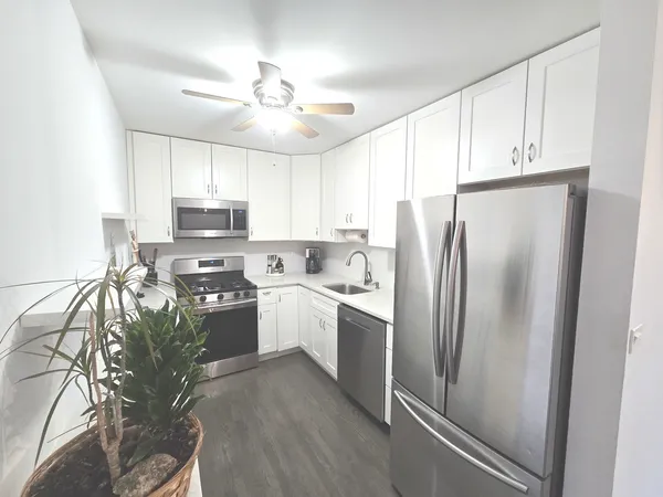 a kitchen with stainless steel appliances a refrigerator sink and white cabinets