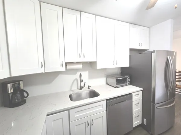 a kitchen with stainless steel appliances a sink a refrigerator a window and cabinets