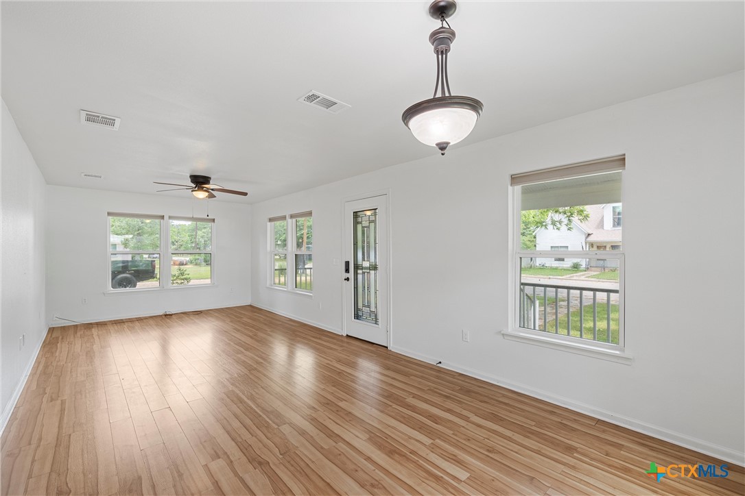 407 East 7th Street Cameron, TX 76520 - Photo 12 of 43 an empty room with wooden floor windows and exposed radiator