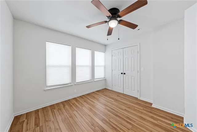 a view of empty room with wooden floor and fan