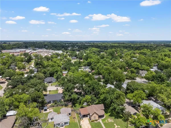 an aerial view of residential houses with outdoor space and trees