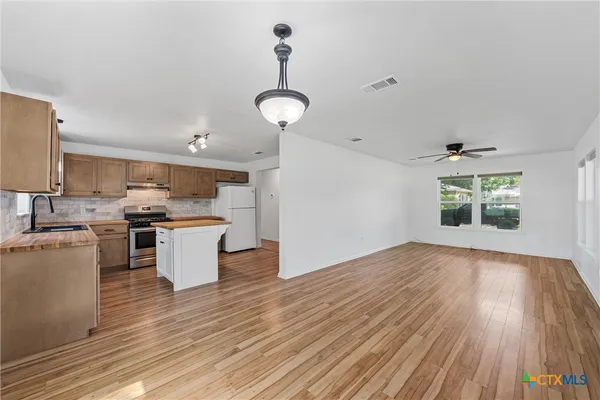 a view of a kitchen with wooden floor and stainless steel appliances