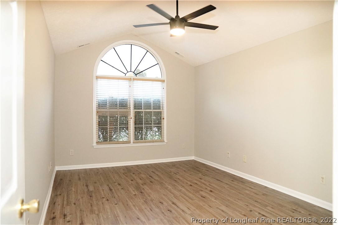2940 Bakers Mill Road Fayetteville, NC 28306 - Photo 25 of 46 an empty room with wooden floor a ceiling fan and windows
