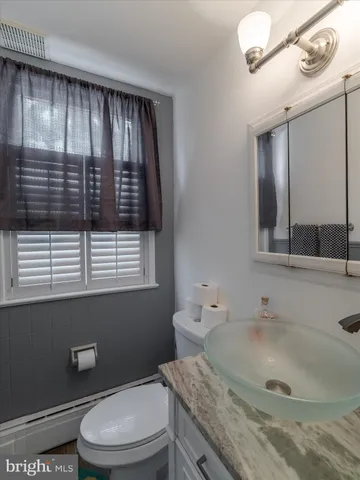 a bathroom with a granite countertop sink mirror vanity and toilet
