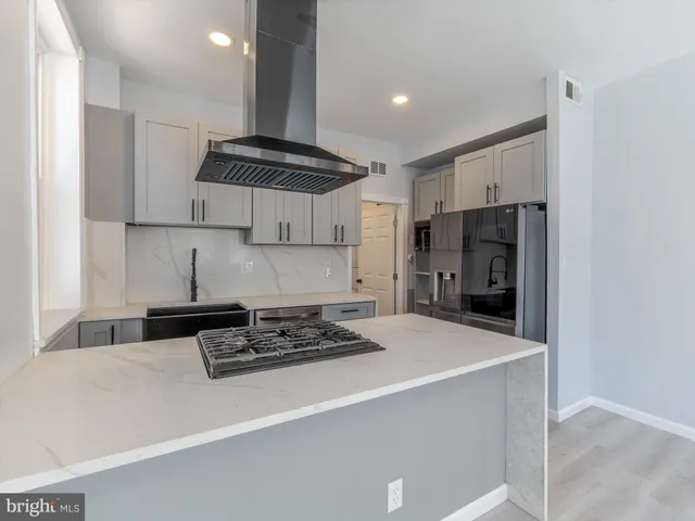 a kitchen with stainless steel appliances a refrigerator a stove a sink and white cabinets